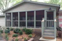 Custom screened porch addition with full-view screens and gabled roof design built by Pro Deck & Design in Kansas City, providing bug-free outdoor living space with professional landscaping for Leavenworth County homeowners