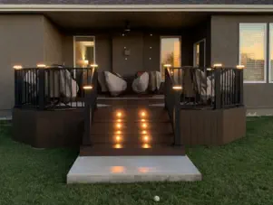 Elegant custom composite deck with integrated LED lighting built by Pro Deck & Design in Kansas City, featuring black metal railings, illuminated stairs, and comfortable seating area for evening entertainment