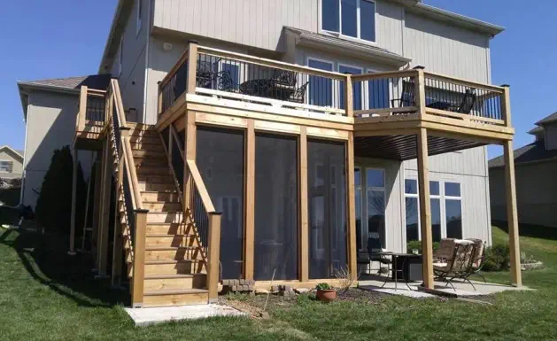 Custom two-level outdoor living solution by Pro Deck & Design in Kansas City featuring elevated cedar deck with black metal railings, professional staircase installation, and screened porch beneath for year-round enjoyment in Johnson County homes
