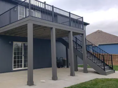Modern elevated deck with black aluminum railings built by Pro Deck & Design in Kansas City, featuring covered patio space underneath, stylish staircase, and contemporary design perfect for maximizing outdoor living space in Wyandotte County homes