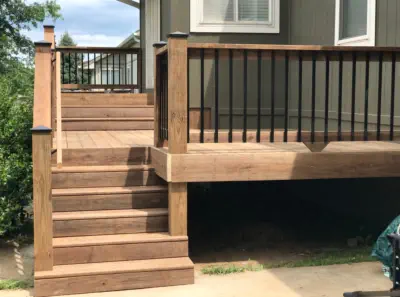 Custom cedar deck with black aluminum balusters built by Pro Deck & Design in Kansas City, featuring professional staircase construction, quality craftsmanship, and elevated design providing extra storage space for Johnson County homeowners