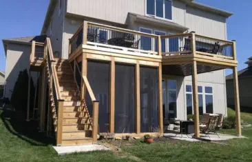 Custom two-level outdoor living solution by Pro Deck & Design in Kansas City featuring elevated cedar deck with black metal railings, professional staircase installation, and screened porch beneath for year-round enjoyment in Johnson County homes
