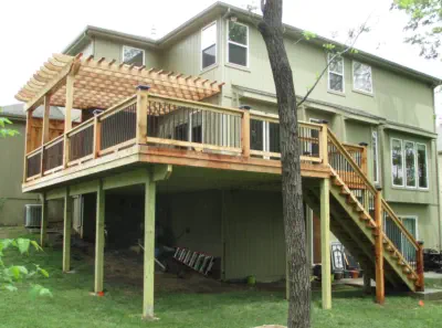 Custom elevated cedar deck with attached pergola built by Pro Deck & Design in Kansas City, featuring professional staircase installation, quality railings, and maximized usable space underneath for Leavenworth County homeowners