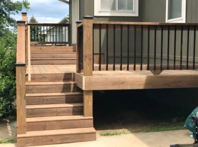 Custom cedar deck with black aluminum balusters built by Pro Deck & Design in Kansas City, featuring professional staircase construction, quality craftsmanship, and elevated design providing extra storage space for Johnson County homeowners