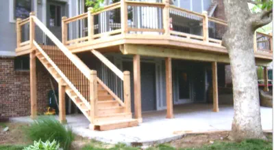 Elevated cedar deck with covered patio space underneath built by Pro Deck & Design in Kansas City, featuring custom staircase, black metal railings, and expert craftsmanship creating dual outdoor living areas for Johnson County homes