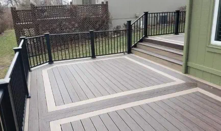 Custom two-tone composite deck installation in Kansas City featuring designer border accents, quality black aluminum railings, and professional craftsmanship built to withstand Kansas's seasonal weather challenges