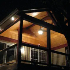 Custom covered deck in Johnson County Kansas with cedar ceiling and professional lighting installation, featuring quality nighttime outdoor living design by expert Kansas contractors specializing in all-season entertainment spaces