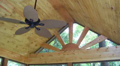 Custom vaulted cedar ceiling in Kansas City screened porch featuring professional carpentry, sunburst window design, and quality construction by experienced Kansas contractors specializing in premium outdoor living spaces