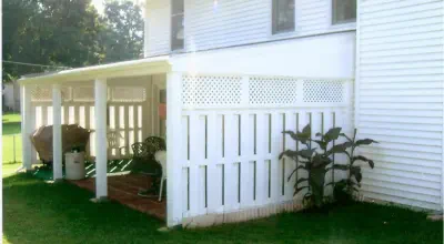 Custom white covered porch in Kansas City featuring professional lattice privacy screens, quality construction, and practical design by experienced Kansas contractors specializing in affordable outdoor living enhancements
