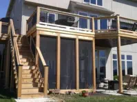 Custom two-level outdoor living solution by Pro Deck & Design in Kansas City featuring elevated cedar deck with black metal railings, professional staircase installation, and screened porch beneath for year-round enjoyment in Johnson County homes