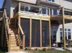 Custom two-level outdoor living solution by Pro Deck & Design in Kansas City featuring elevated cedar deck with black metal railings, professional staircase installation, and screened porch beneath for year-round enjoyment in Johnson County homes