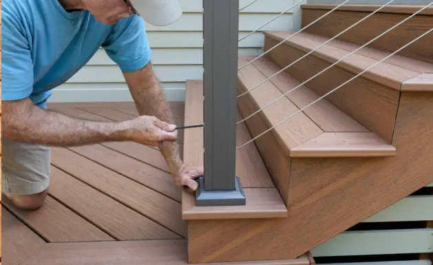 Professional deck repair and installation by Pro Deck & Design craftsman in Kansas City, showing precision drilling technique on composite deck stairs during quality renovation service in Johnson County