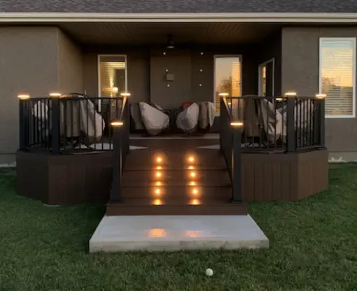 Elegant custom composite deck with integrated LED lighting built by Pro Deck & Design in Kansas City, featuring black metal railings, illuminated stairs, and comfortable seating area for evening entertainment