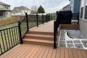 Modern composite deck with black aluminum railings installed by Pro Deck & Design in Kansas City, featuring built-in outdoor kitchen area, custom steps, and durable low-maintenance decking perfect for Leavenworth County weather conditions