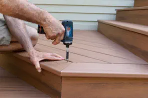 Professional deck repair and installation by Pro Deck & Design craftsman in Kansas City, showing precision drilling technique on composite deck stairs during quality renovation service in Johnson County